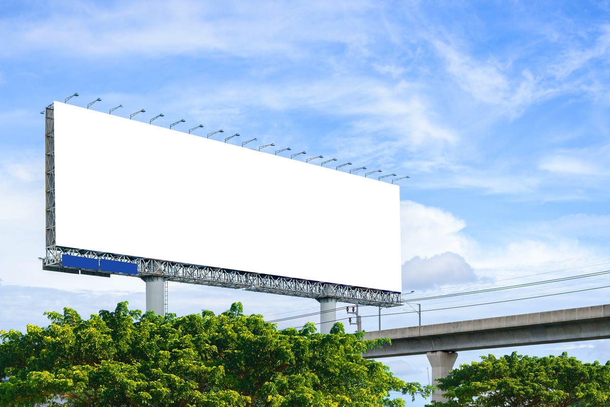 Blank billboard frame mounted in a city street against a sky background (stock image)